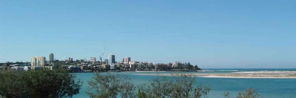 Caloundra beach with calm waves and a clear sky.