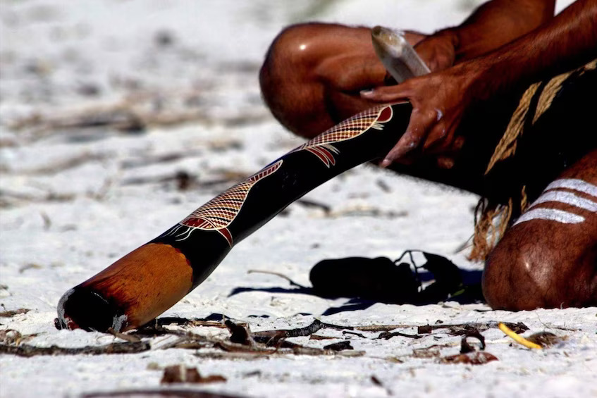 Man holding a didgeridoo on beach